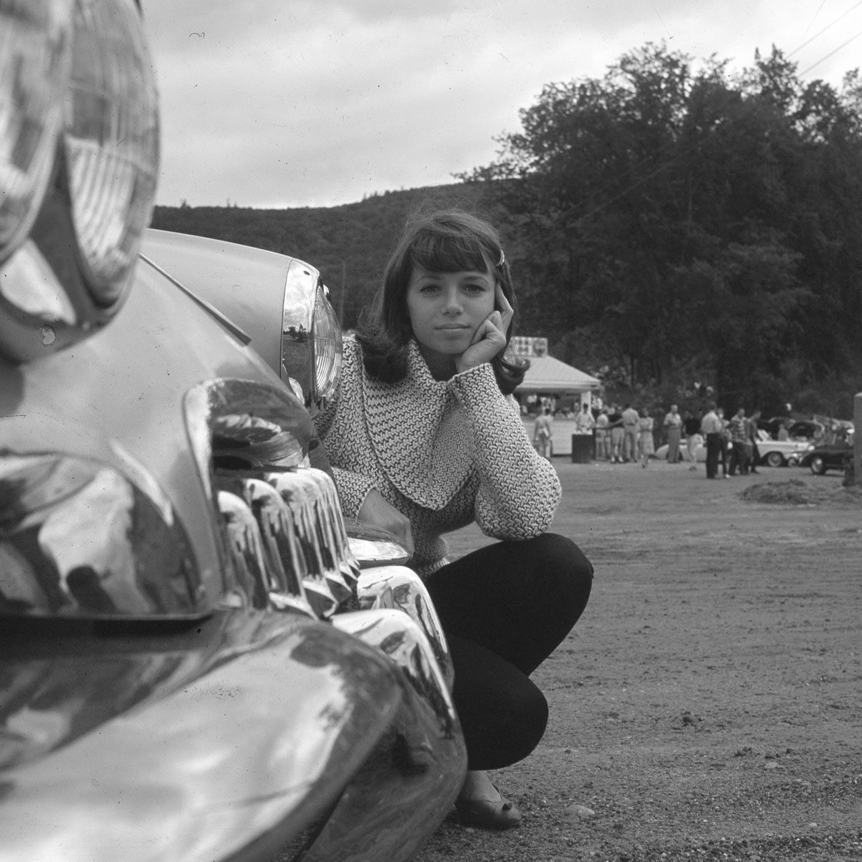 Ronnie Haran seated beside a Corvette in the 1960s